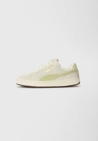 Niedrig geschnittene Puma Suede Sneaker in Off-White mit einem hellgrünen Wildlederstreifen und goldenem Logo an der Seite, cremefarbenen Schnürsenkeln und brauner Sohle.