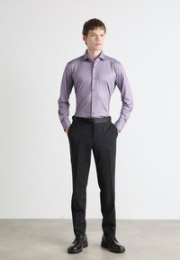 Light purple button-up shirt with a smooth texture, paired with tailored black trousers and black lace-up shoes, standing against a neutral background.