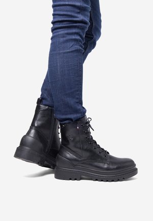 Black leather ankle boots feature a lace-up design, rounded toe, durable rubber sole, and a side zipper for easy wear.
