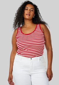 Rød- og hvidstribet tanktop med ribbet tekstur og brede stropper, parret med hvide højtaljede jeans.