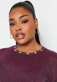 Fioletowy sweter z metaliczną nicią, z okrągłym dekoltem ozdobionym złotymi oczkami. Gładka tekstura i dopasowany krój.