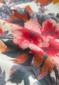 Tessuto con stampa floreale che presenta vivaci tonalità di rosso, giallo e verde su uno sfondo crema. Texture morbida con una leggera lucentezza. Dettagli accentuati in stile acquarello.