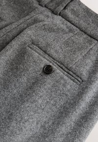 Gray wool trousers featuring a flat front, a single back pocket with a black button, and a soft, textured finish.