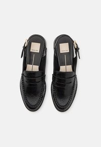 Black leather slingback shoes with a moccasin design, featuring a textured finish, decorative stitching, and a gold-tone hardware accent.