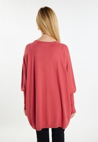 Pulover coral supradimensionat, cu mâneci lungi, textură moale și croială largă. Prezintă un decolteu rotund și un tiv canelat. Design simplu și curat.