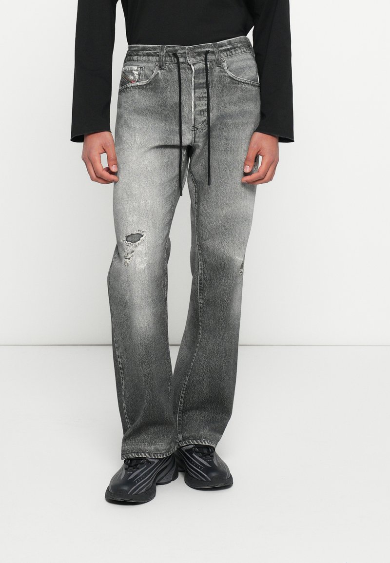 Γκρι τζιν παντελόνια από τζιν ύφασμα με ξεθωριασμένο πλύσιμο. Διαθέτουν φθαρμένες λεπτομέρειες, κανονικές τσέπες και κλείσιμο με κορδόνι στη μέση. Συνδυασμένα με μαύρα παπούτσια.