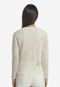 Stickad krämfärgad tröja med ett rutmönstrat spetsdesign, långa ärmar och rund halsringning, med ribbad fåll och manschetter.