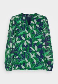 Bloes met bloemenprint op een marineblauwe achtergrond, met groene bladeren en witte bloemen. Lichtgewicht stof, lange mouwen en een V-hals ontwerp.