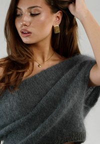 Grå fuzzy uld off-the-shoulder top med en tekstureret finish, parret med guldøreringe med bølgemønster og en guldhjerteformet halskæde.