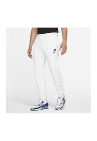 Vita sweatpants med elastisk midja och mudd. Försedd med Nike-logotyper i svart och blått. Stiliserad med grå och blå sportskor.