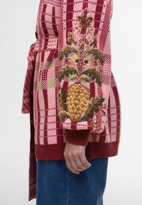 Καρό κατόμι με κόκκινο και ροζ χρώμα, διακοσμημένο με �κεντημένα λουλούδια και ανανάδες. Έχει ζώνη στη μέση και ριμπ μανσέτες. Φτιαγμένο από υφασμάτινη υφή.