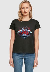 T-shirt in cotone nero con una stampa grafica di teschi multicolori, punte e la parola "Slayer" in lettere rosse in grassetto al centro.