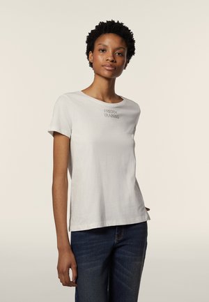 T-shirt bianco a maniche corte con la scritta "FREDDY TRAINING" ricamata sul petto in un font semplice, abbinato a jeans blu. Tessuto morbido, vestibilità rilassata.