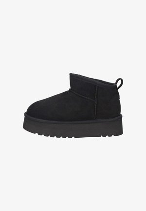 Stivaletti neri in suede con suola in gomma spessa, dettagli cuciti e un'asola sul retro.
