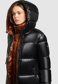 Zwarte pufferjack met een glanzende afwerking, capuchon en bruin satijnen voering, met ritszakken en een prominent logo op de mouw.