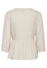 Top peplum in beige chiaro, con scollatura rotonda, maniche a tre quarti e vita arricciata per una silhouette svasata. Texture del tessuto liscia.