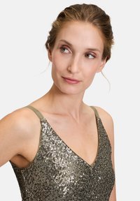 Haut sans manches en sequins vert olive avec un décolleté en V. Présente une silhouette ajustée et une texture brillante grâce à des sequins superposés.