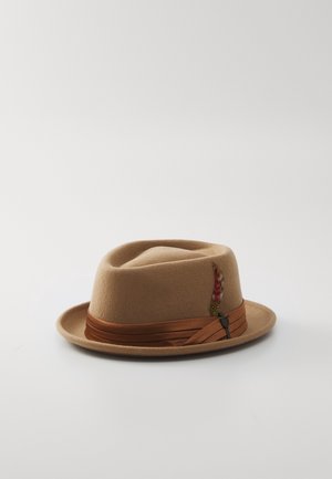 Lichtbruine vilten fedora hoed met een donkerbruine lintband en een kleine decoratieve rode en beige veer aan de zijkant.