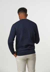 Marinblå sweatshirt med rund halsringning, lång ärm och ribbad mudd, med en slät textur och en avslappnad passform.