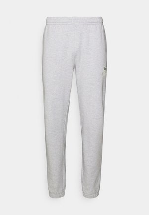 Pantalones de chándal grises con una cinturilla y puños elásticos, fabricados en suave material de algodón. Presentan un pequeño logo verde y sin patrones visibles.