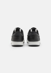 Black athletic shoes with a smooth leather finish, white rubber soles, and a cushioned interior, featuring subtle stitching details.