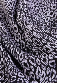 Tissu en coton présentant un motif monochrome de formes abstraites en blanc et noir, affichant une texture lisse avec un léger éclat.