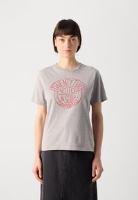 Graues Baumwoll-T-Shirt mit kurzen Ärmeln, das einen roten Grafikdruck mit der Aufschrift "TWENTY TWO SCOTCH & SODA AMSTERDAM" zeigt. Sanfte Textur.