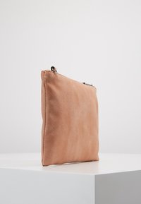 Miękka różowa kopertówka zamszowa o płaskim, prostokątnym kształcie, z prostym metalowym zamkiem na górze, bez widocznych ozdobnych elementów metalowych.