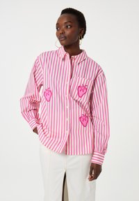 Pink and white striped button-up shirt with embroidered strawberry designs on the chest and pocket. Features loose fit and long sleeves.