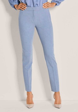 Lichtblauwe, op maat gemaakte broek met een gladde textuur, een smalle pasvorm en rechte pijpen, gecombineerd met beige hoge hakken.