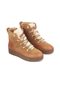 Stivaletti in suede marrone con fodera in shearling sintetico, hardware oro e suola in gomma con motivo. Presentano una cerniera laterale e una chiusura con lacci.
