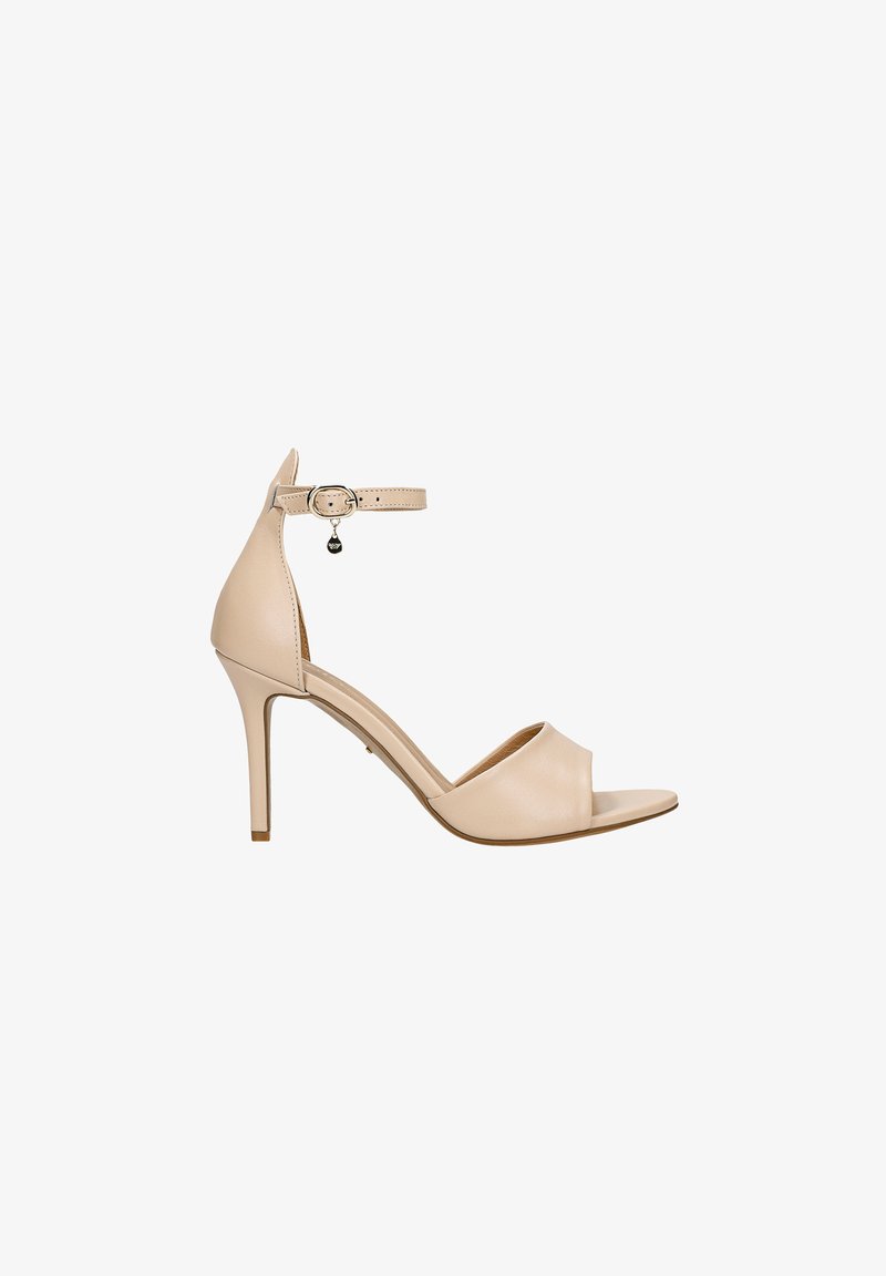 Sandale à talon haut en cuir beige avec une pointe ouverte, une sangle à cheville réglable et un détail de breloque circulaire sur la sangle. Texture lisse.