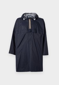 Maritim vanntett regnponcho med hette, vertikal glidelås og frontlomme. Har hvite snorer og stripete detaljer på glidelåsen.