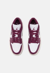 Paire de baskets Air Jordan bordeaux et blanches avec lacets, boîte à bouts perforée et logo Jumpman sur la languette, vue de dessus sur un fond blanc.