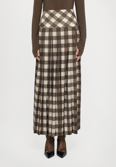 Falda de cuadros marrón y beige con pliegues, que presenta una cintura ajustada y bolsillos laterales. Combinada con botas marrones, realzando la textura del conjunto.