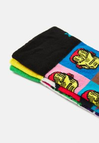 Chaussettes en coton colorées présentant différents motifs. Les couches comprennent des sections noires, vertes, jaunes, roses et bleues ornées d'illustrations. Texture douce.