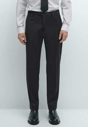 Dark pinstriped trousers made of fabric, featuring a slim fit, flat-front design, and a button closure, paired with black leather shoes.