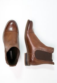 Brązowe skórzane botki za kostkę z elastycznymi bocznymi panelami, zaokrąglonym noskiem, ozdobnym przeszyciem i niskim, podpartym obcasem.