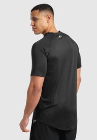 Camisa deportiva negra de manga corta, con un diseño ajustado y un escote redondo. Tejido texturizado y detalle del logo en la parte posterior del escote.