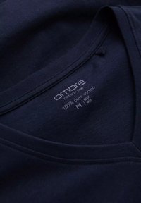 Tmavě námořnická modrá bavlněná tričko s V-výstřihem, se štítkem s názvem značky "ombre", složením a informacemi o velikosti.