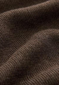 Gros plan d'un tissu tricoté brun foncé montrant une texture côtelée fine et des plis doux.