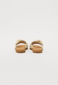 Lys beige sandaler med en myk overdel i et kryssdesign og en glatt, brun gummisåle. Har en bred stropp og minimalistisk stil.