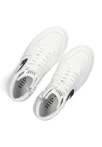 Witte hoge sneakers van leer, met een geperforeerde neus, zwarte logo-accenten en witte veters. Merken binnenin de enkel.