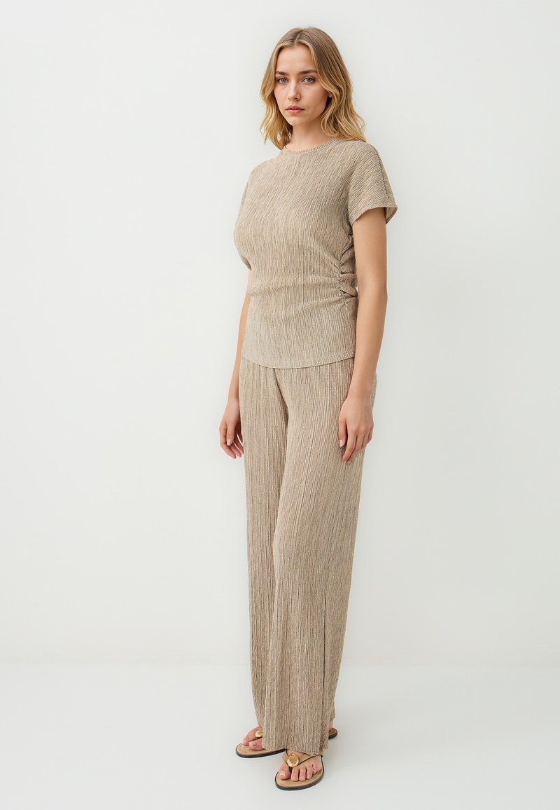 Beige geribbelde gebreide top en wijde broek set, met een gestructureerd oppervlak en korte mouwen. Verfraaid met subtiele metallic draden.