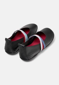 Zapatos de cuero negro con puntera redonda y correas elásticas en azul claro, rojo y blanco. El interior presenta un forro rojo contrastante.