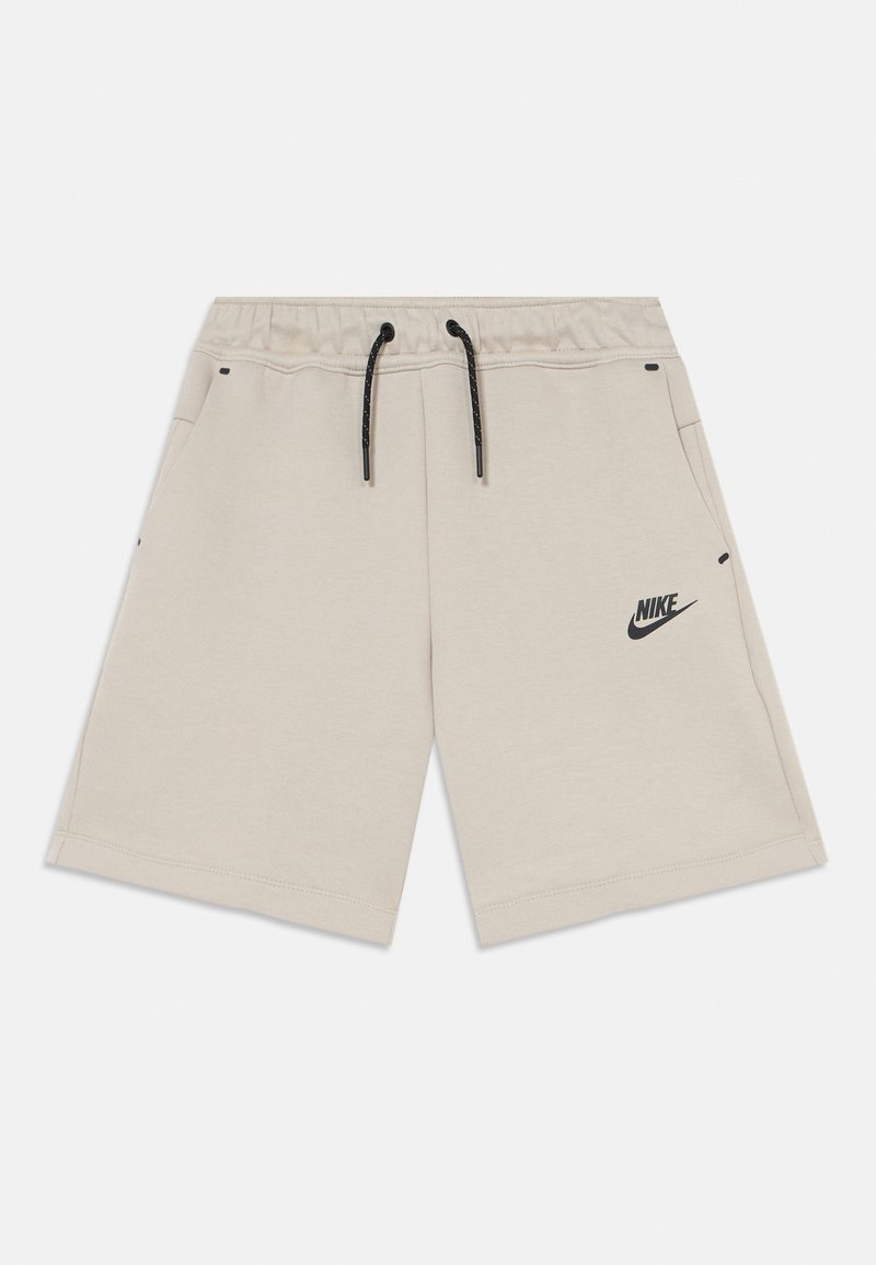 Beige cotton shorts with an elastic waistband and black drawstring, featuring side pockets and a black Nike logo on the left side.