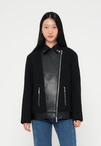 Μαύρο υφασμάτινο μπουφάν με δερμάτινη επένδυση, ασημένιους φερμουάρ και κολάρο. Διαθέτει δύο μπροστινές τσέπες με φερμουάρ. Κατάλληλο για επίστρωμα.