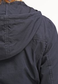 Dark navy hooded jacket with a smooth texture, featuring stitched details and a slightly relaxed fit, focusing on the back view.