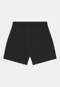 Pantalones cortos de algodón negro con cintura elástica, que cuentan con un bolsillo trasero y dobladillo enrollado, textura suave y diseño informal.