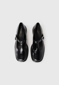Črni usnjeni čevlji s T-trakom, zaobljenim prstom in gladko, sijočo teksturo ter majhnim zaponkom na strani.